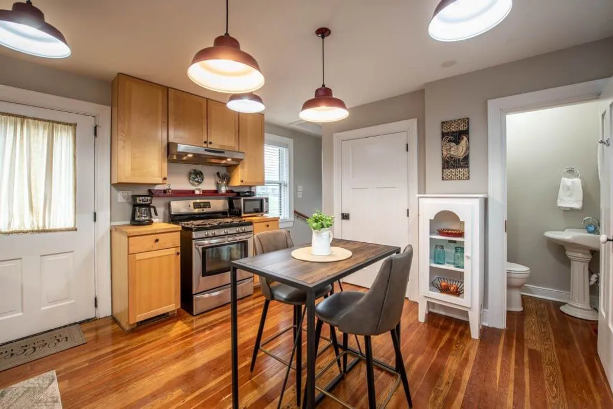 A modern kitchen with a central island, stainless steel appliances, hanging light fixtures, and decorative wall art. The kitchen island is inviting for casual meals, food preparation, or gathering with friends, while the appliances and layout indicate a fully equipped space ready for any culinary adventure.