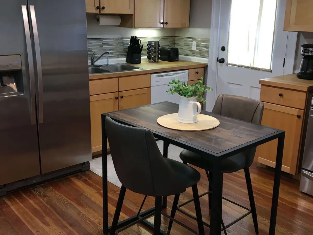 A cozy and functional kitchen scene featuring a kitchen table, essential appliances, and cabinetry. The space feels practical for both meal prep and relaxed dining, with ample room for family or friends to gather before a day of exploration.
