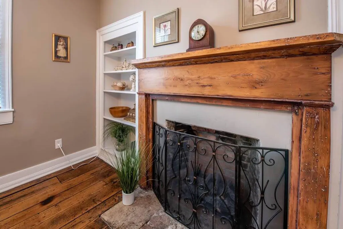 A cozy living space featuring a stately fireplace with a wooden mantel, shelves displaying decor, and tasteful wall art. The inviting setting encourages gatherings and quiet evenings by the fire.