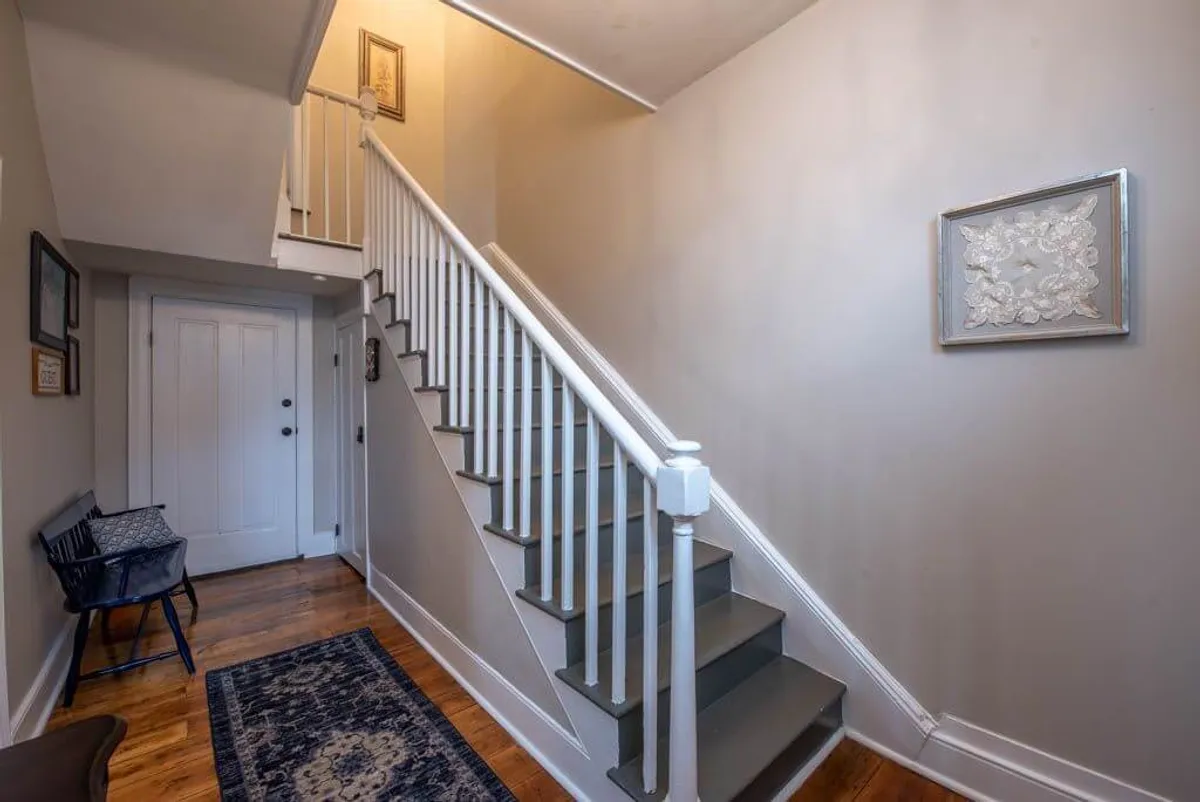 This image captures the welcoming entryway of the home, featuring an elegant staircase, inviting wall art, and a comfortable bench. The scene evokes a sense of arrival and anticipation, suggesting guests preparing to head out to explore or returning from a vibrant night downtown.